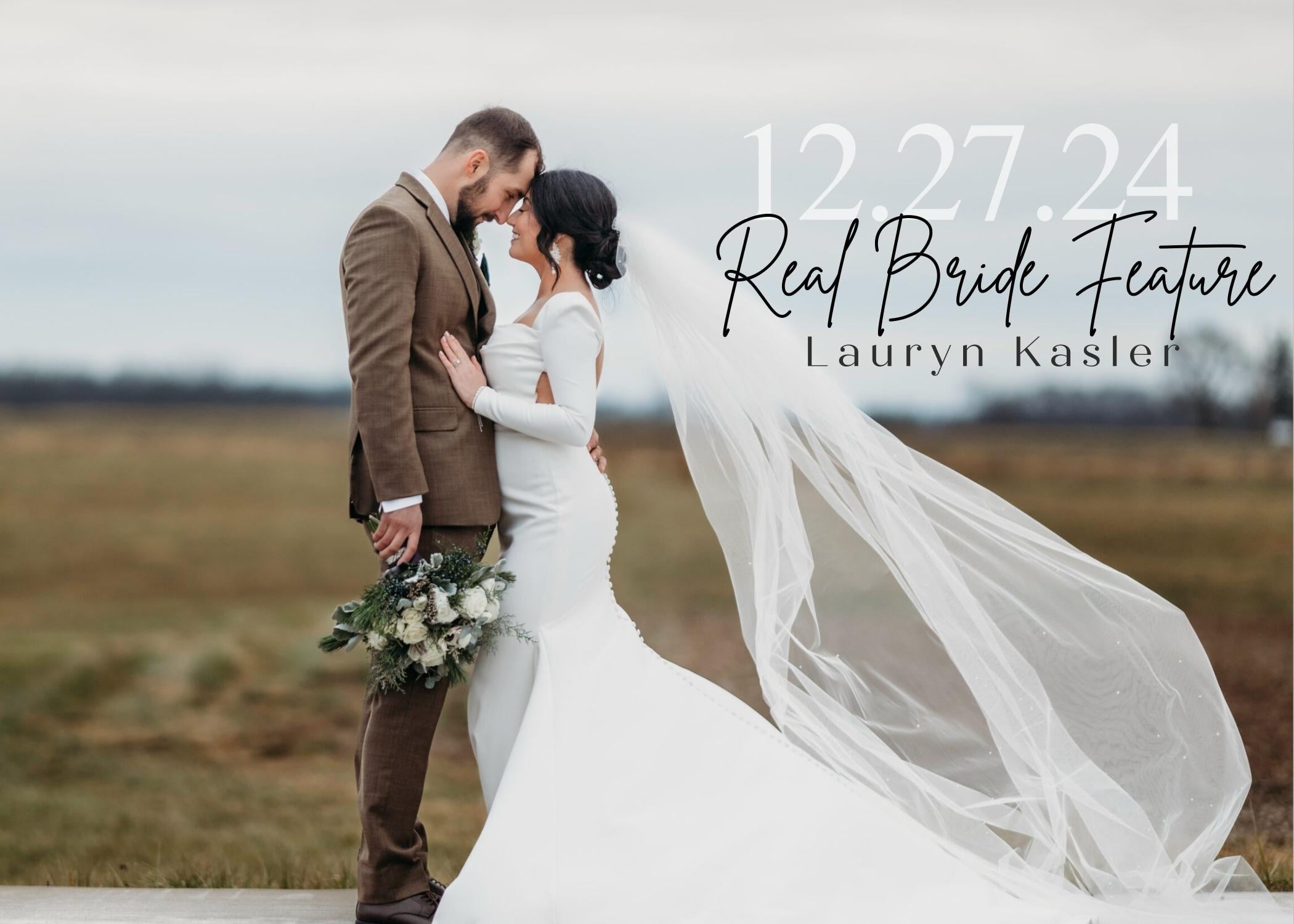 Bride Lauryn Kasler embracing her groom in an open field, wearing a fitted long-sleeve wedding gown with a dramatic flowing veil, holding a white and green bouquet during their winter wedding.