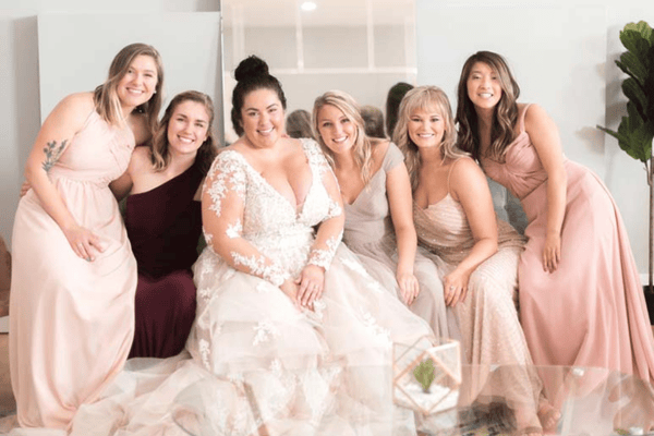 A bride in her wedding dress and her bridesmaids in different yet cohesive bridesmaid dresses