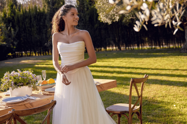 A bride in her wedding gown standing beside the table
