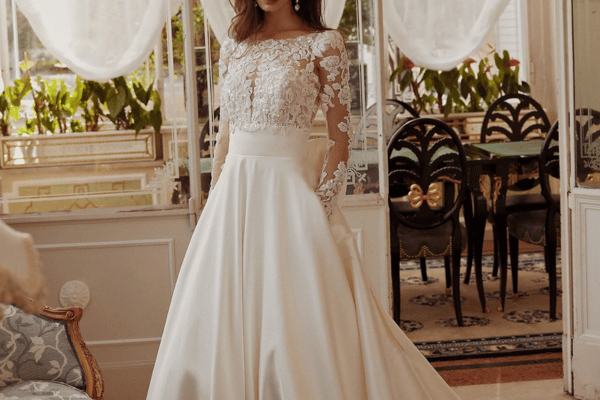 A bride in her wedding dress with illusion neckline, hands in her pockets