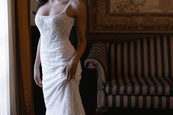 Bride wearing a sheath wedding dress silhouette with a slim, body-skimming fit.
