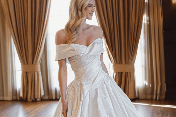 Bride wearing an off-the-shoulder ball gown wedding dress with a structured bodice and full skirt.