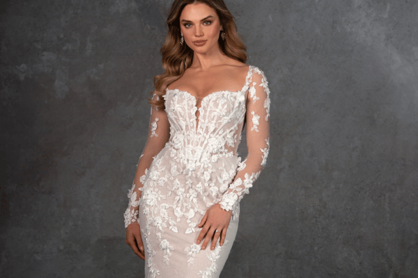Bride wearing a fitted lace wedding dress with long illusion sleeves and floral appliqués
