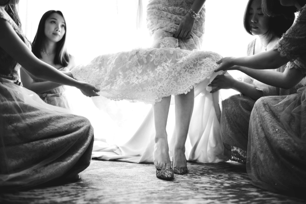 Bridesmaids helping fasten a wedding dress bustle before the reception.