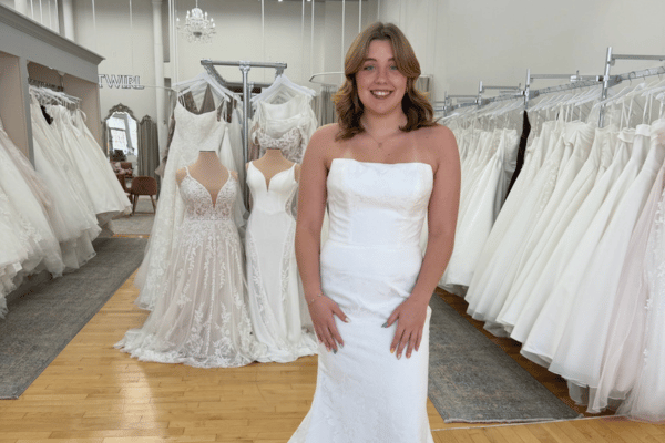 Smiling bride wearing a fitted strapless wedding dress in a bridal boutique.