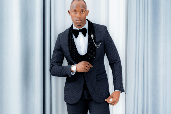 Groom wearing a textured black tuxedo with a black bow tie and pocket chain.